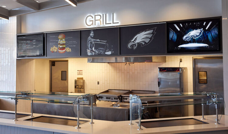 una postazione di cucina e griglia con BrightSign digital signage riprodotto su schermi sopra un ventilatore industriale